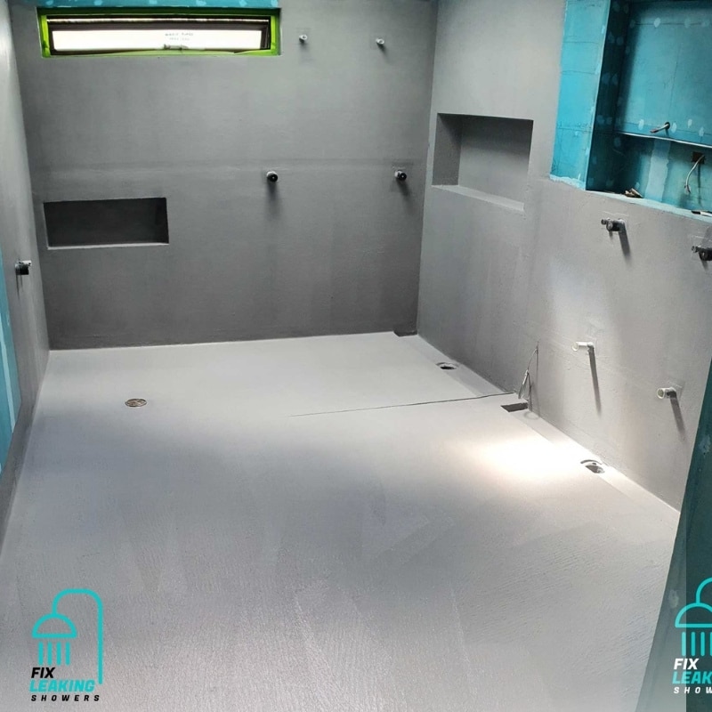 Newly renovated shower space with gray walls and floor, plumbing fixtures, and window, perfect to fix leaking showers in Dawes Point.